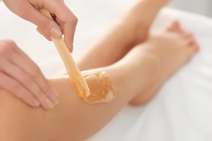 Leg waxing treatment with warm wax application in a professional beauty salon