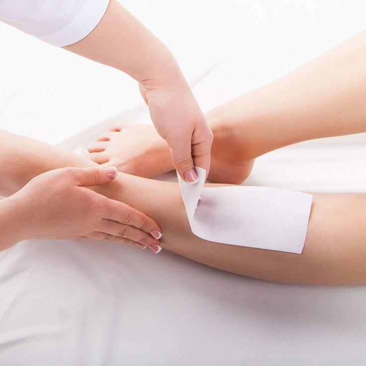Professional aesthetician performing lower leg wax strip removal at Brooklyn Brows NYC