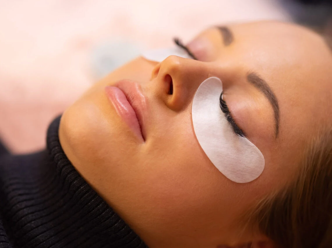 Lash technician applying perming solution during an eyelash lift procedure