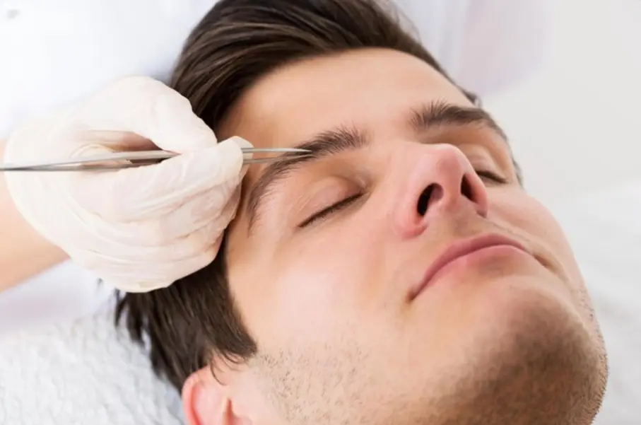 Technician performing eyebrow threading on a male client